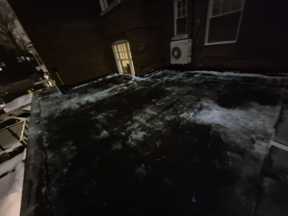Rooftop terrace by a door with snow cleared away at night